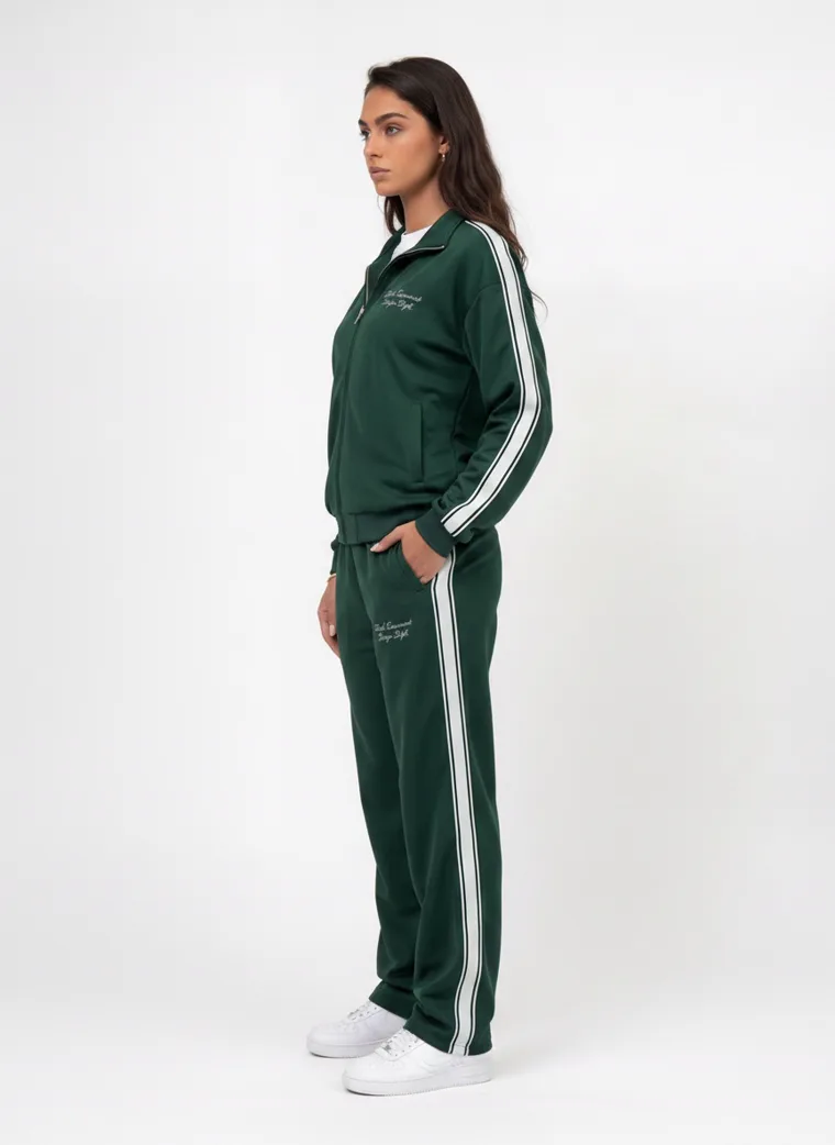 A forest green track jacket and pants with white side stripes and small embroidered chest text on pale grey. Track Jacket and Pants in Forest, frame 3 of 5