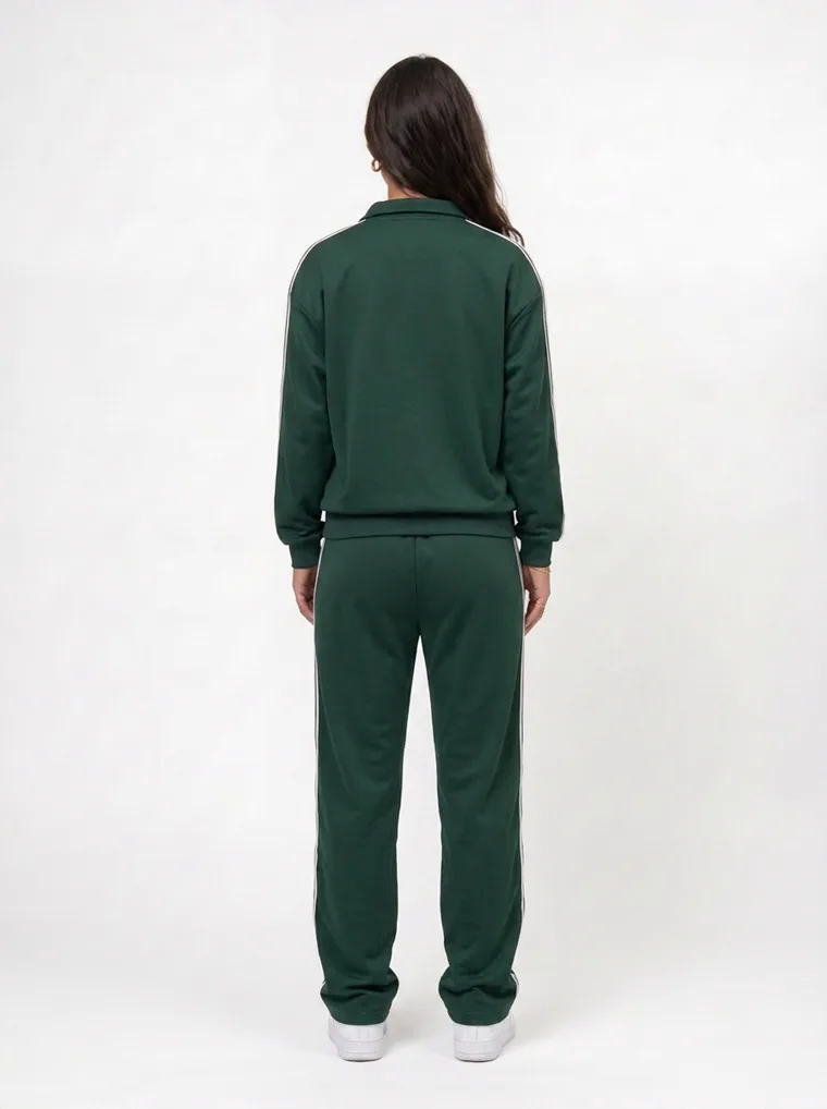 A forest green track jacket and pants with white side stripes and small embroidered chest text on pale grey. Track Jacket and Pants in Forest, frame 5 of 5