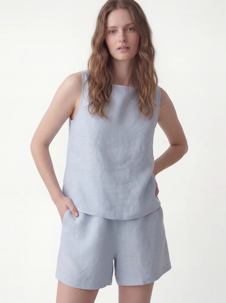 A pale blue linen sleeveless top with matching linen shorts and black flip flops on white. Linen Top and Shorts in Pale Blue, frame 2 of 5