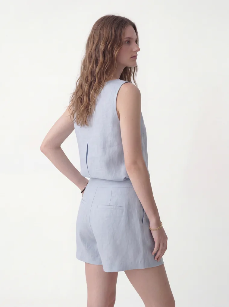 A pale blue linen sleeveless top with matching linen shorts and black flip flops on white. Linen Top and Shorts in Pale Blue, frame 3 of 5