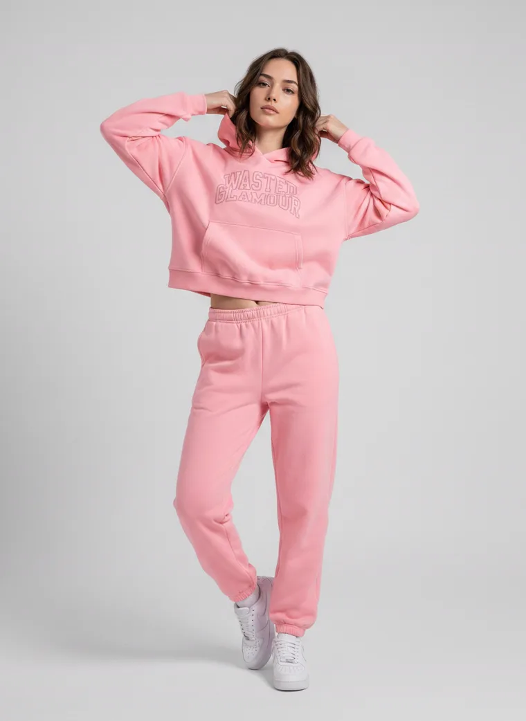 A pink hoodie with tonal collegiate lettering, styled with matching joggers and white sneakers on pale grey. Collegiate Hoodie in Pink, frame 1 of 5