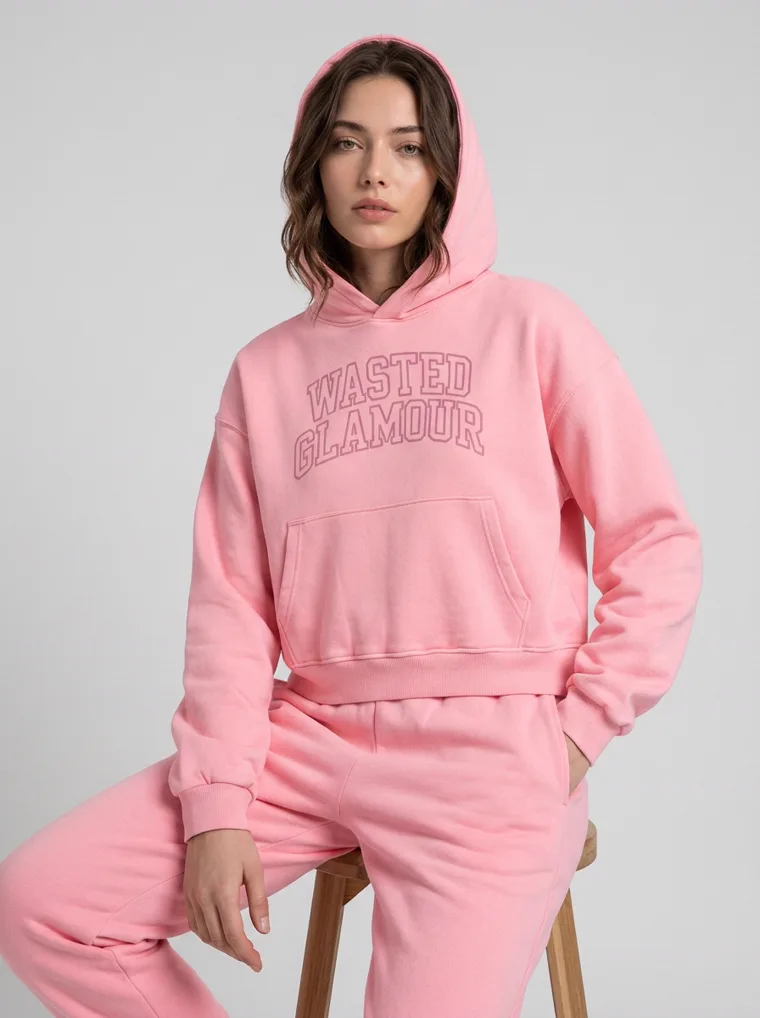 A pink hoodie with tonal collegiate lettering, styled with matching joggers and white sneakers on pale grey. Collegiate Hoodie in Pink, frame 2 of 5