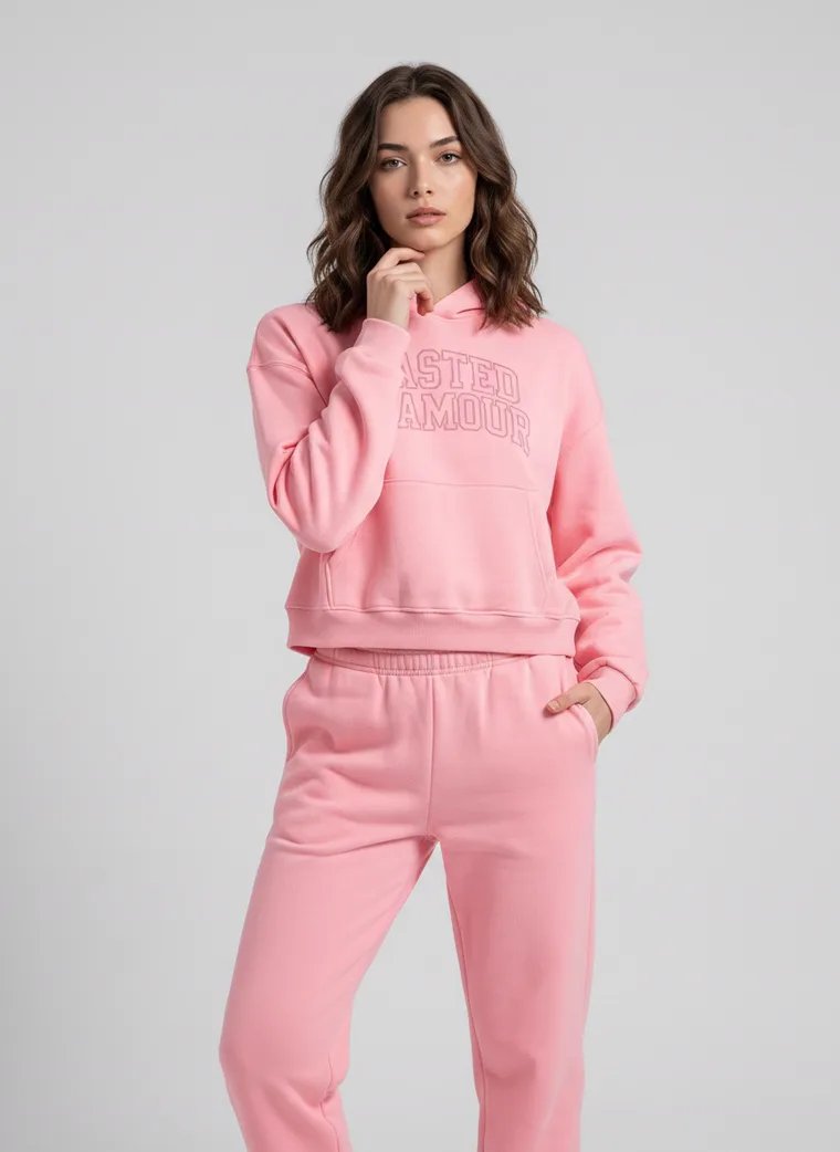 A pink hoodie with tonal collegiate lettering, styled with matching joggers and white sneakers on pale grey. Collegiate Hoodie in Pink, frame 5 of 5