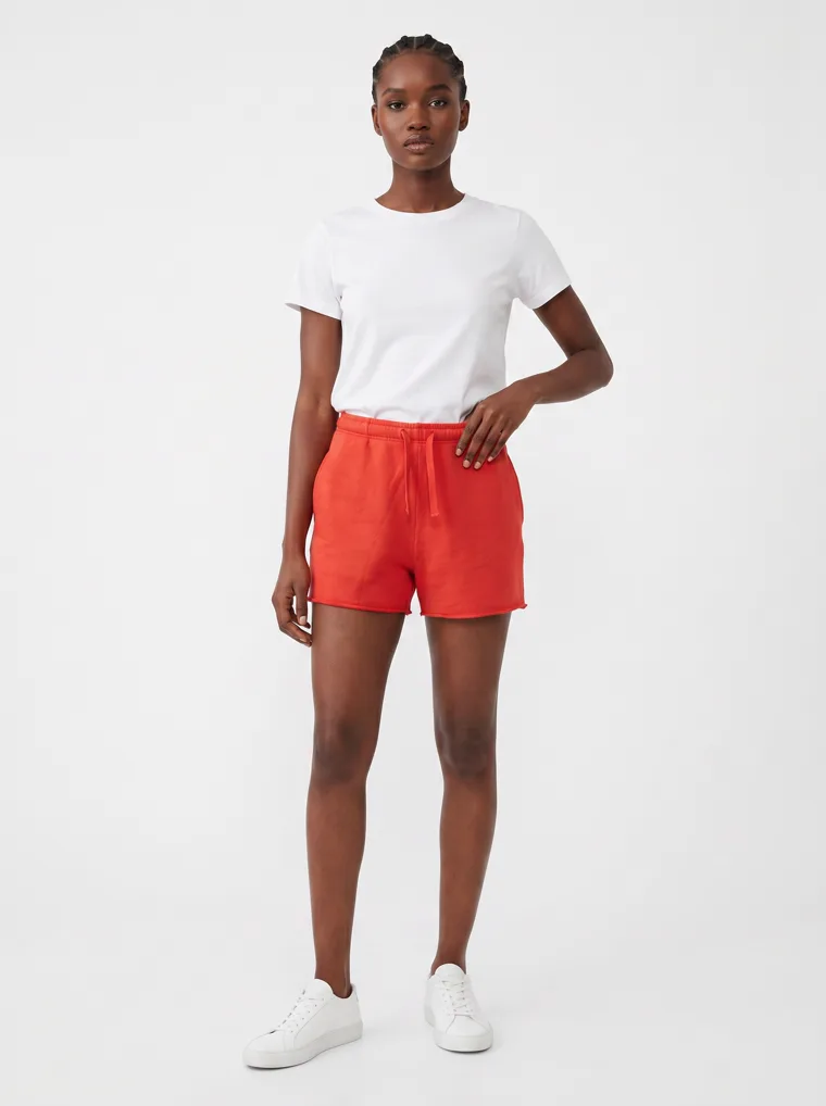 Red drawstring sweat shorts styled with a plain white tee and white sneakers on pale grey. Drawstring Shorts in Red, frame 1 of 5