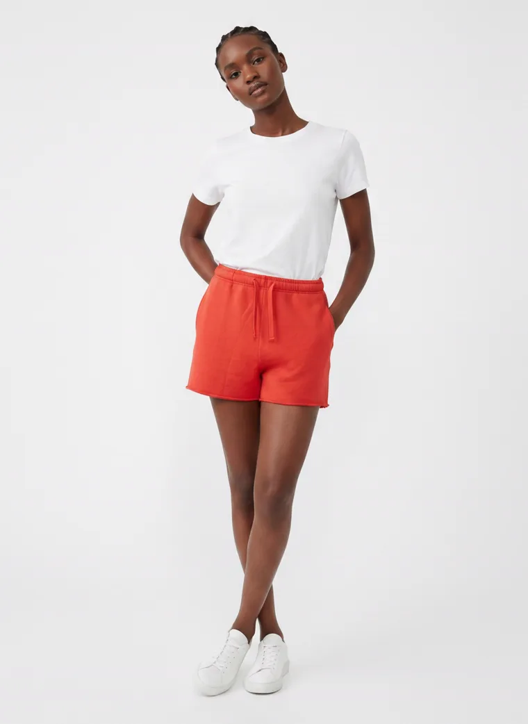 Red drawstring sweat shorts styled with a plain white tee and white sneakers on pale grey. Drawstring Shorts in Red, frame 2 of 5