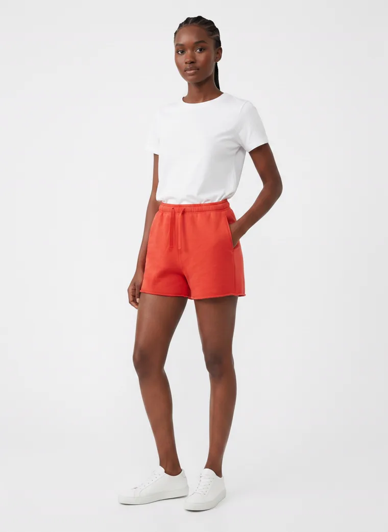 Red drawstring sweat shorts styled with a plain white tee and white sneakers on pale grey. Drawstring Shorts in Red, frame 3 of 5