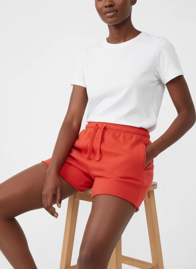 Red drawstring sweat shorts styled with a plain white tee and white sneakers on pale grey. Drawstring Shorts in Red, frame 5 of 5