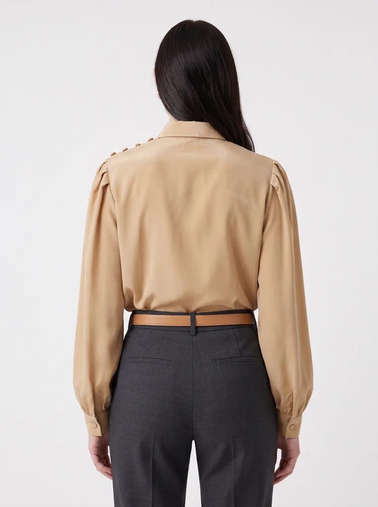 A camel cowl neck blouse with bishop sleeves, worn with charcoal tailored trousers, a tan belt and nude heels on pale grey. Cowl Neck Blouse in Camel, frame 3 of 5