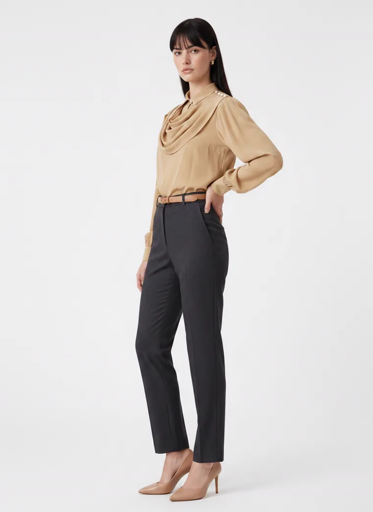 A camel cowl neck blouse with bishop sleeves, worn with charcoal tailored trousers, a tan belt and nude heels on pale grey. Cowl Neck Blouse in Camel, frame 4 of 5