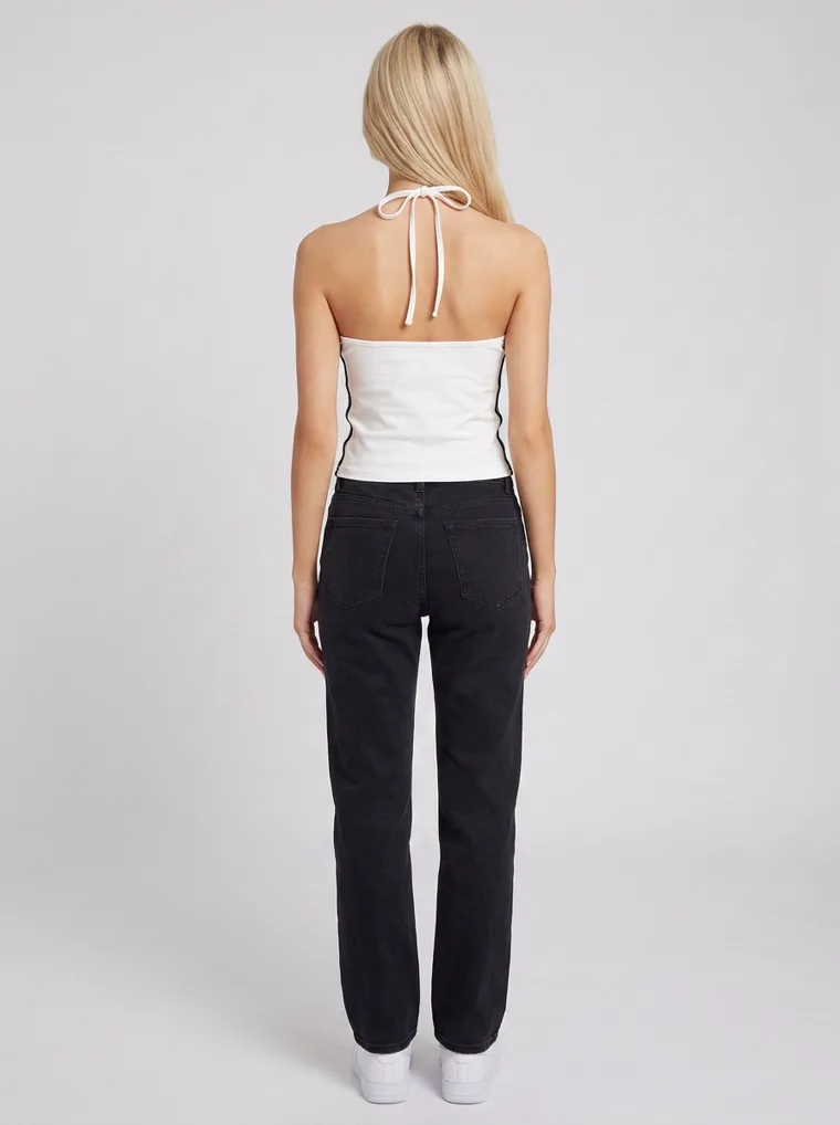 A white halter neck cami with a small chest print, worn with black straight jeans and white sneakers on pale grey. Halter Cami in White, frame 5 of 5