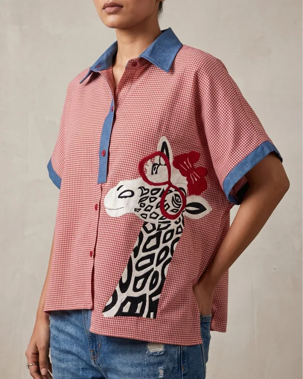 Input photo — a pink checked shirt with an applique motif photographed on a person, cropped at the neck