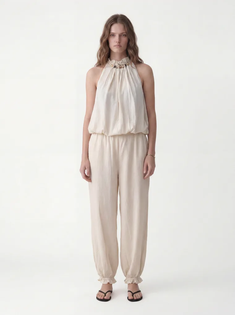 MODA AI output — the cream halter jumpsuit on a full-length model against a clean white studio background