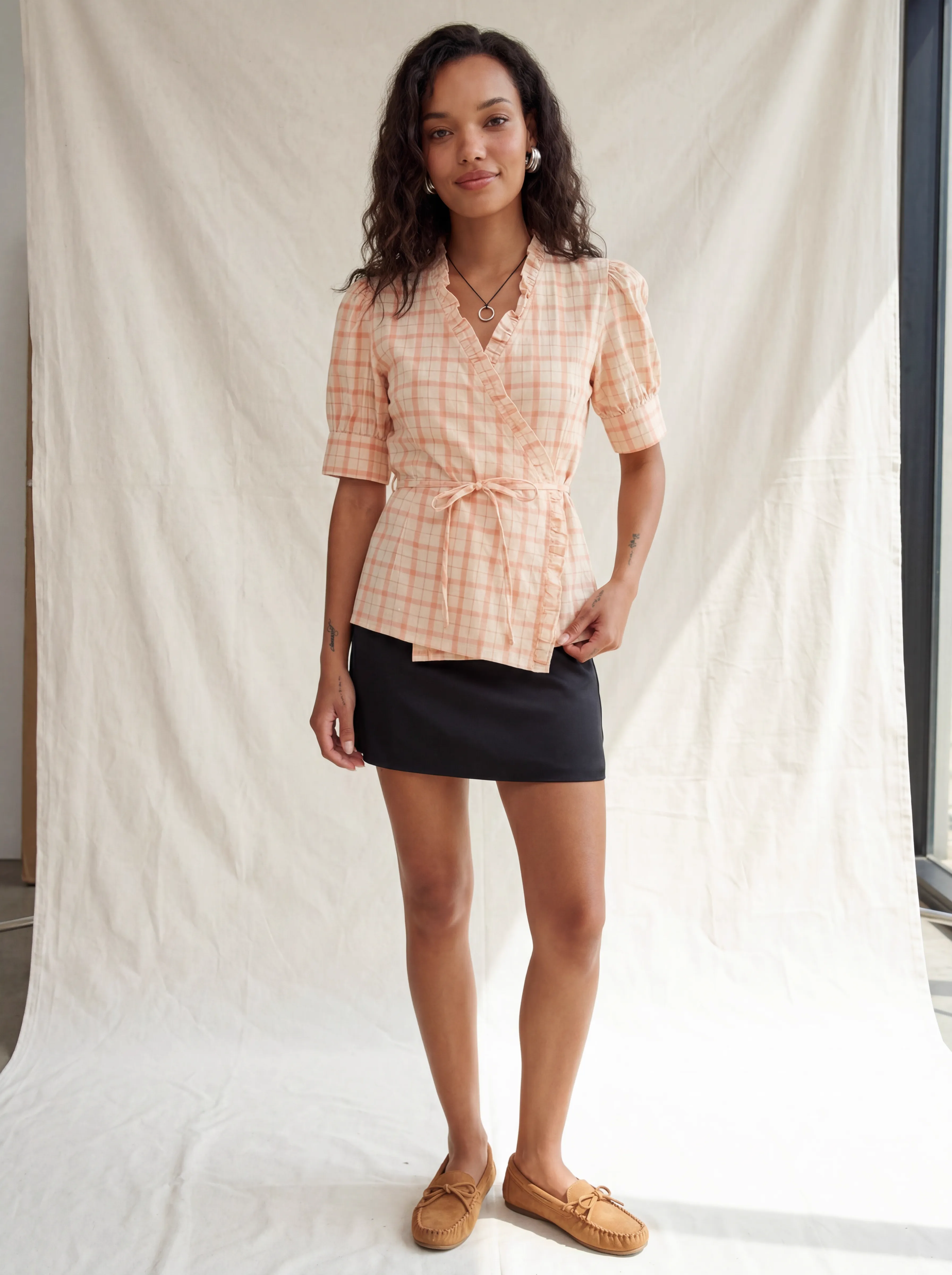MODA AI output 1 — full-body studio model wearing peach plaid wrap top with belt and ruffle detail