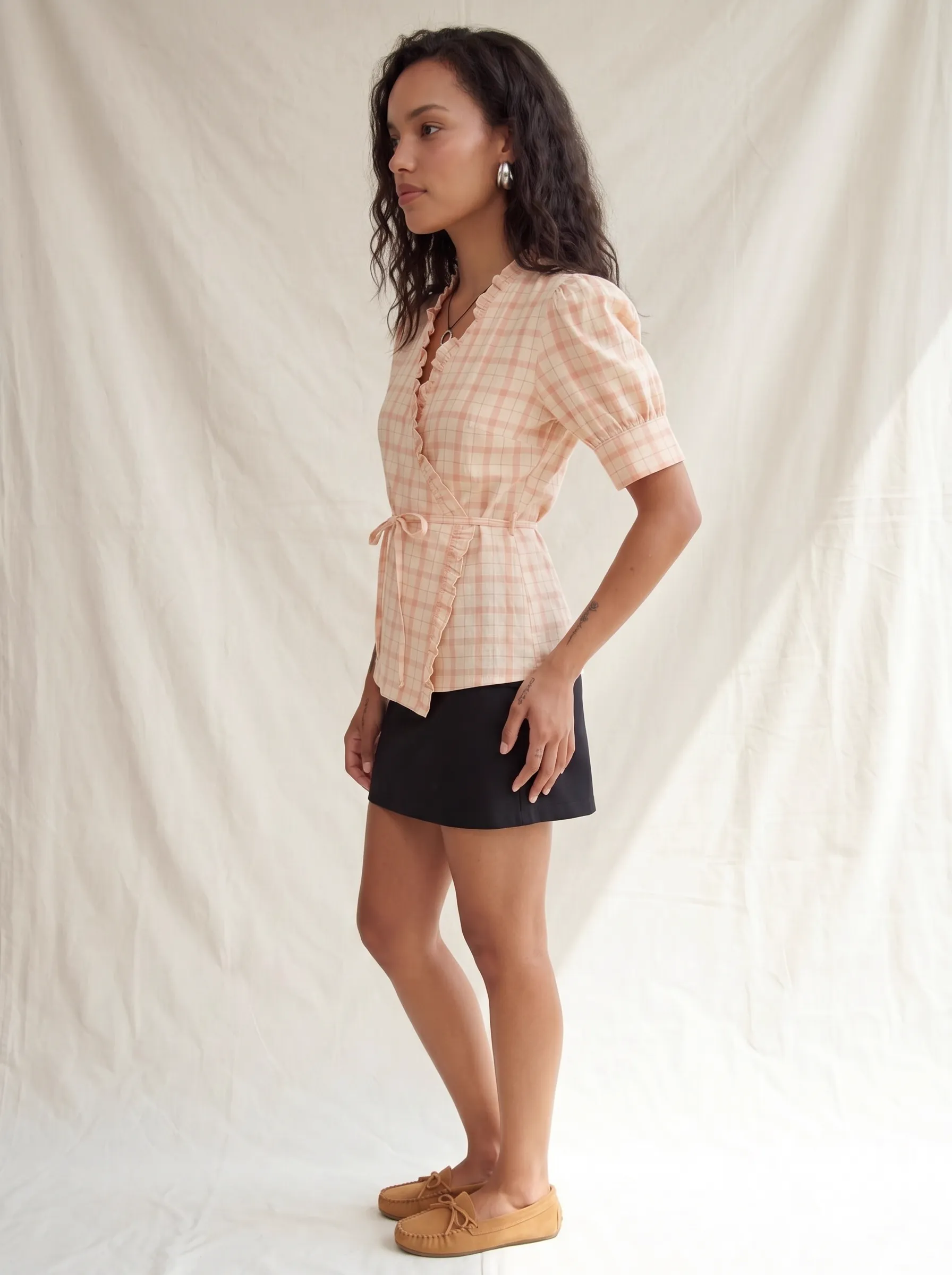 MODA AI output 4 — full-body studio model wearing peach plaid wrap top with belt and ruffle detail