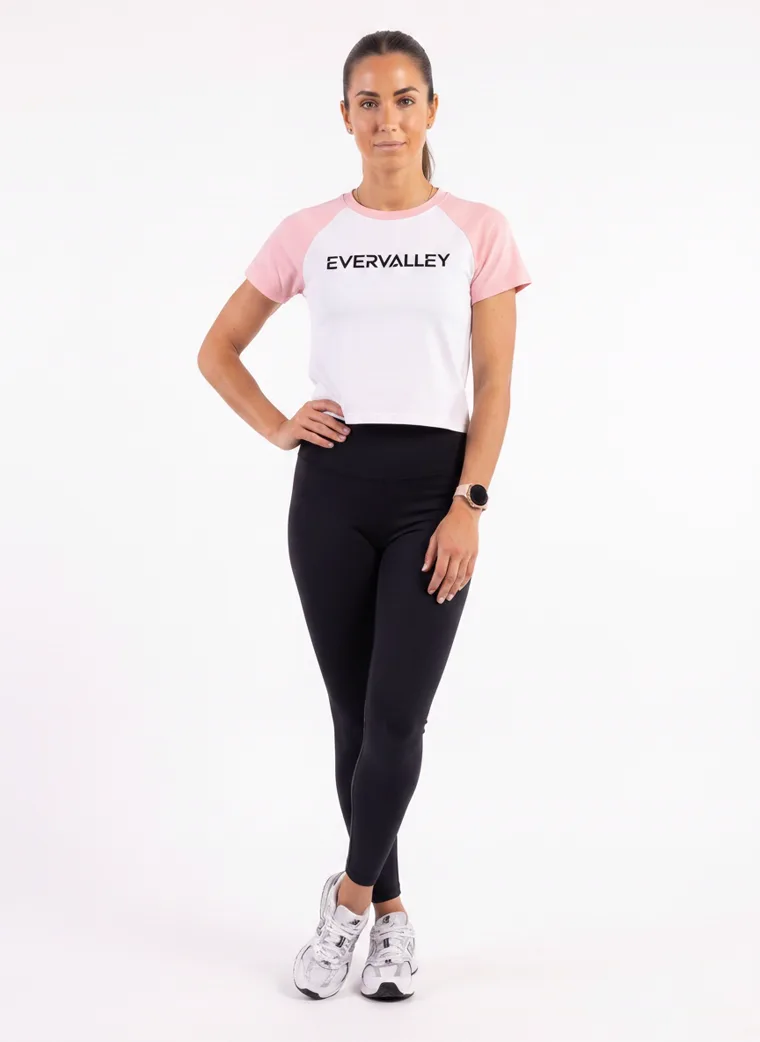 MODA AI output — the raglan tee in blush pink, three-quarter front with hand on hip