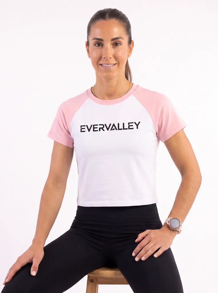 MODA AI output — the raglan tee in blush pink, seated on a stool