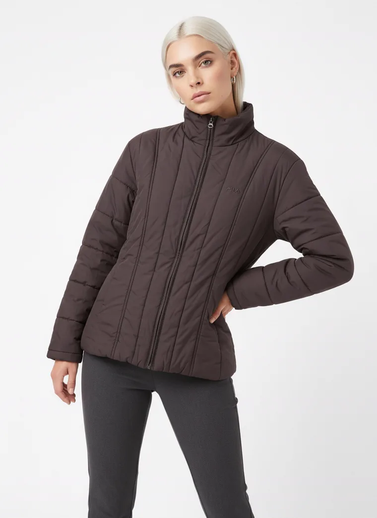 A model in a dark brown channel-quilted puffer, waist-up in three-quarter with a hand in her pocket, the quilted channels catching the light