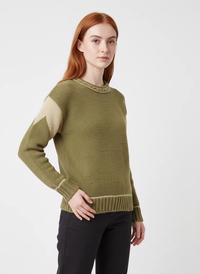 An olive crew-neck knit with tan contrast shoulder panels and cream tipping at the neck and cuffs, worn with black trousers. Knit with Contrast Panels in olive, three-quarter
