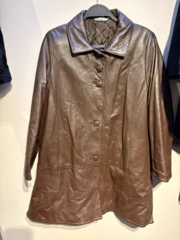 The starting photo for the leather car coat: the leather coat on a hanger against a shop wall