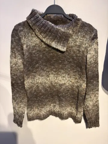 The starting photo for the marled funnel-neck knit: the marled knit on a hanger against a shop wall