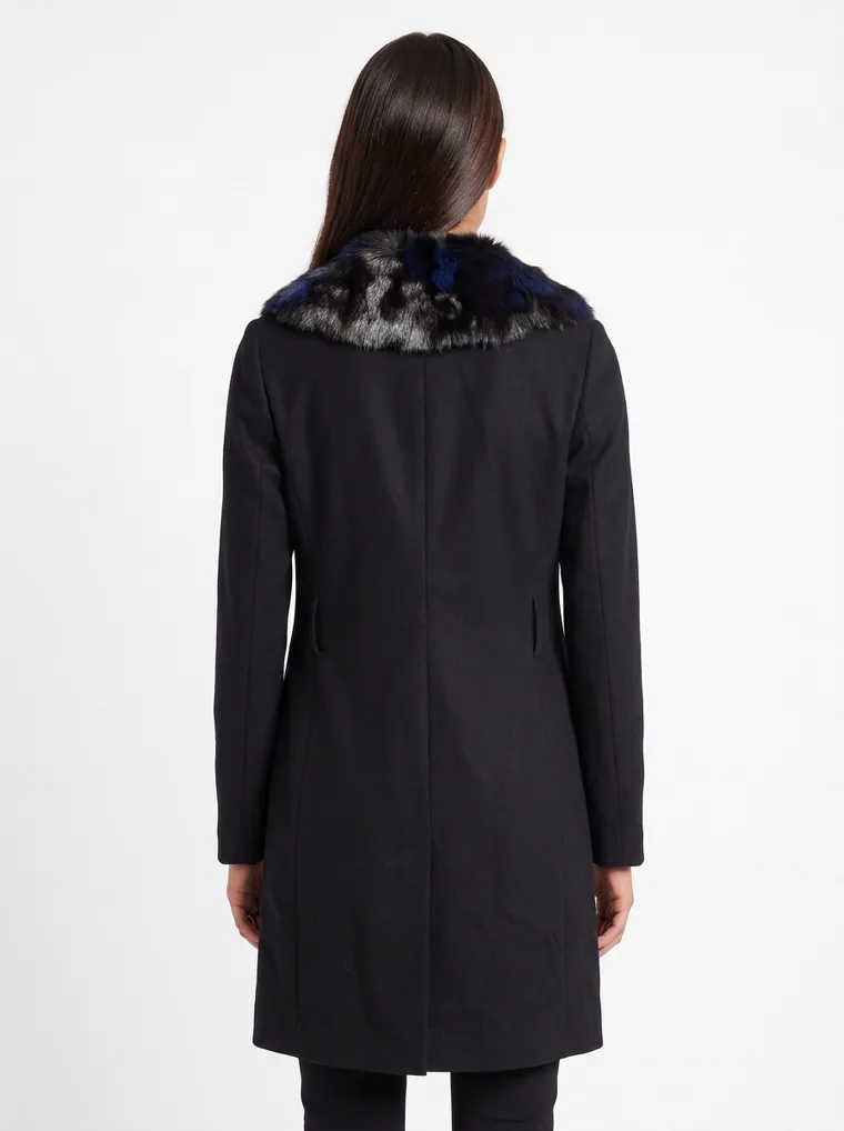 A black single-breasted wool coat with a dark faux-fur collar, worn with black trousers and black boots. Wool Coat with Faux-Fur Collar in black, back view